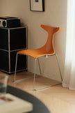 Orange chair in a room with a black cabinet and white curtain.