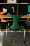 Green chair in a modern office setting with bookshelves and tables.