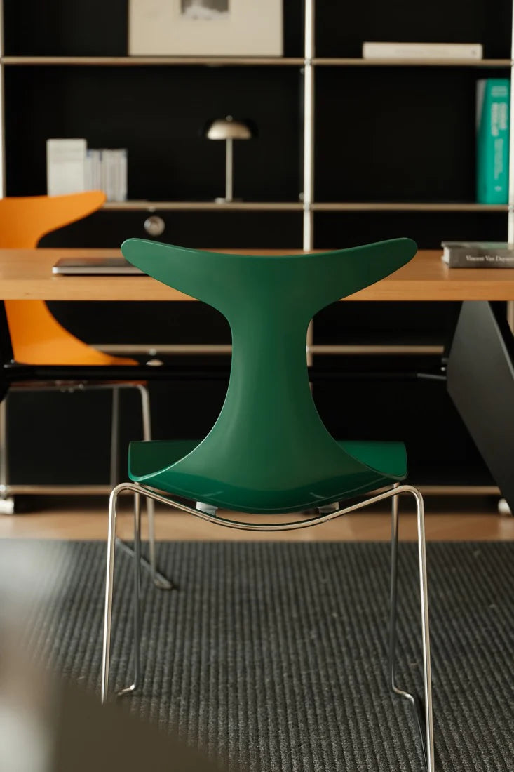 Green chair in a modern office setting with bookshelves and tables.