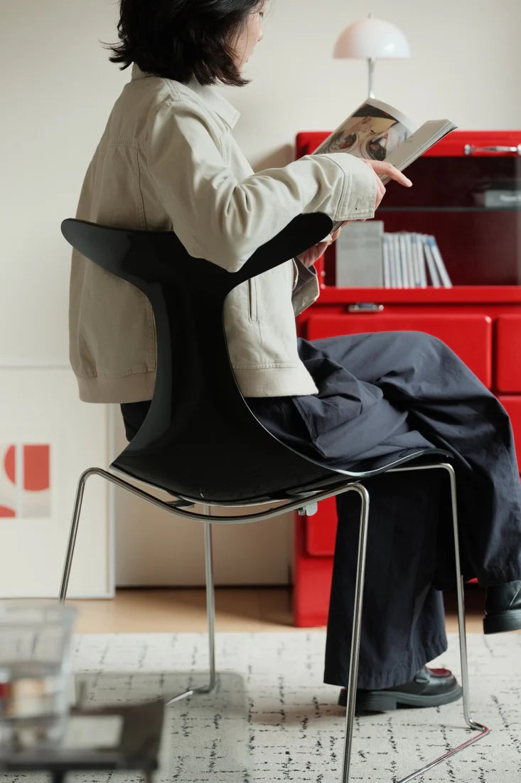 Person sitting on a modern chair reading a book in a room with red cabinets.