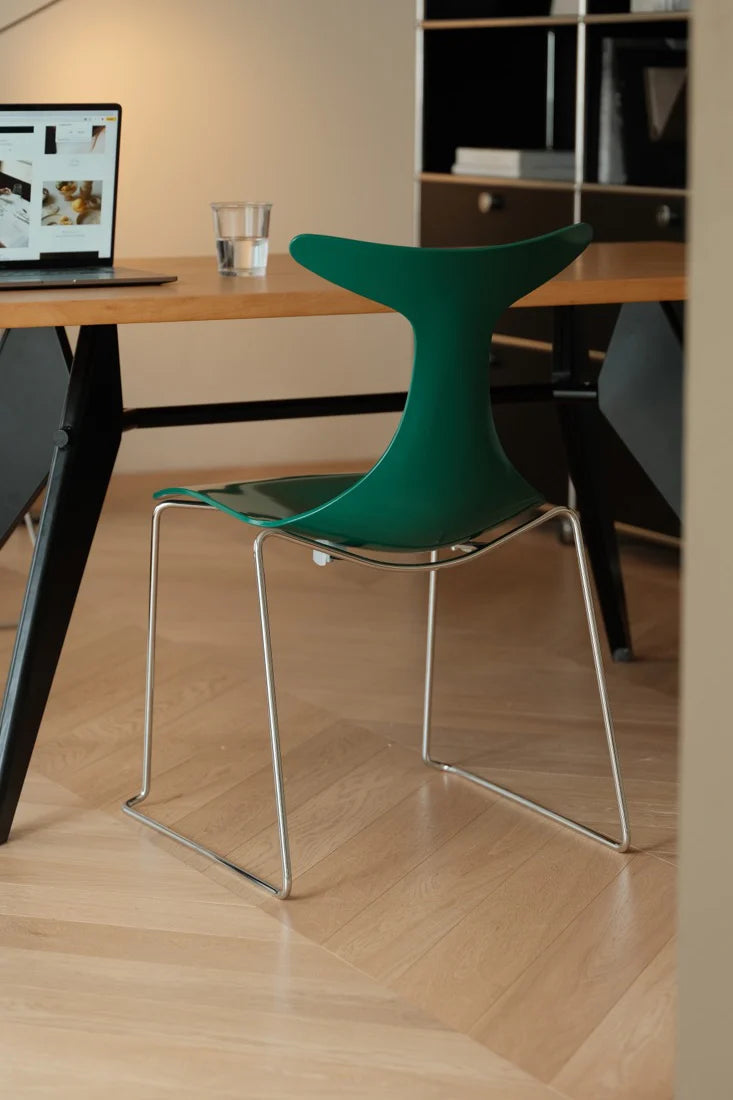 Green chair with metal legs in a room with a desk and computer.