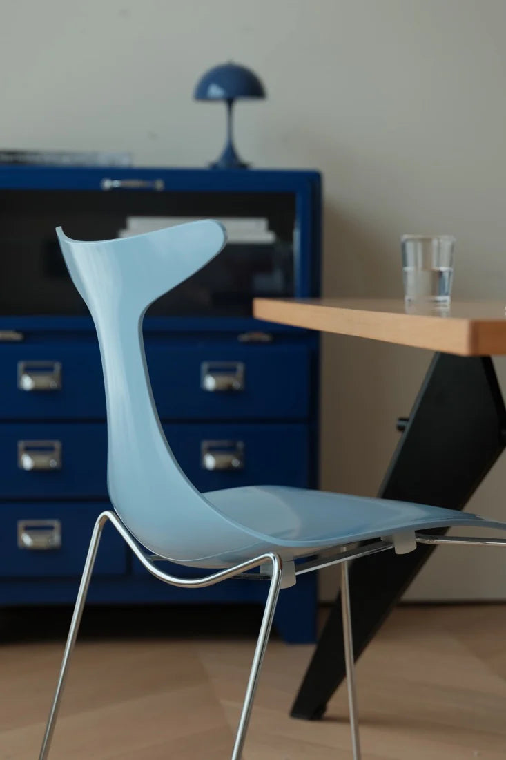 Blue chair in front of a wooden table with a glass on a blurred background