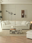 Modern living room with a white sofa, marble coffee table, and wall lamp.
