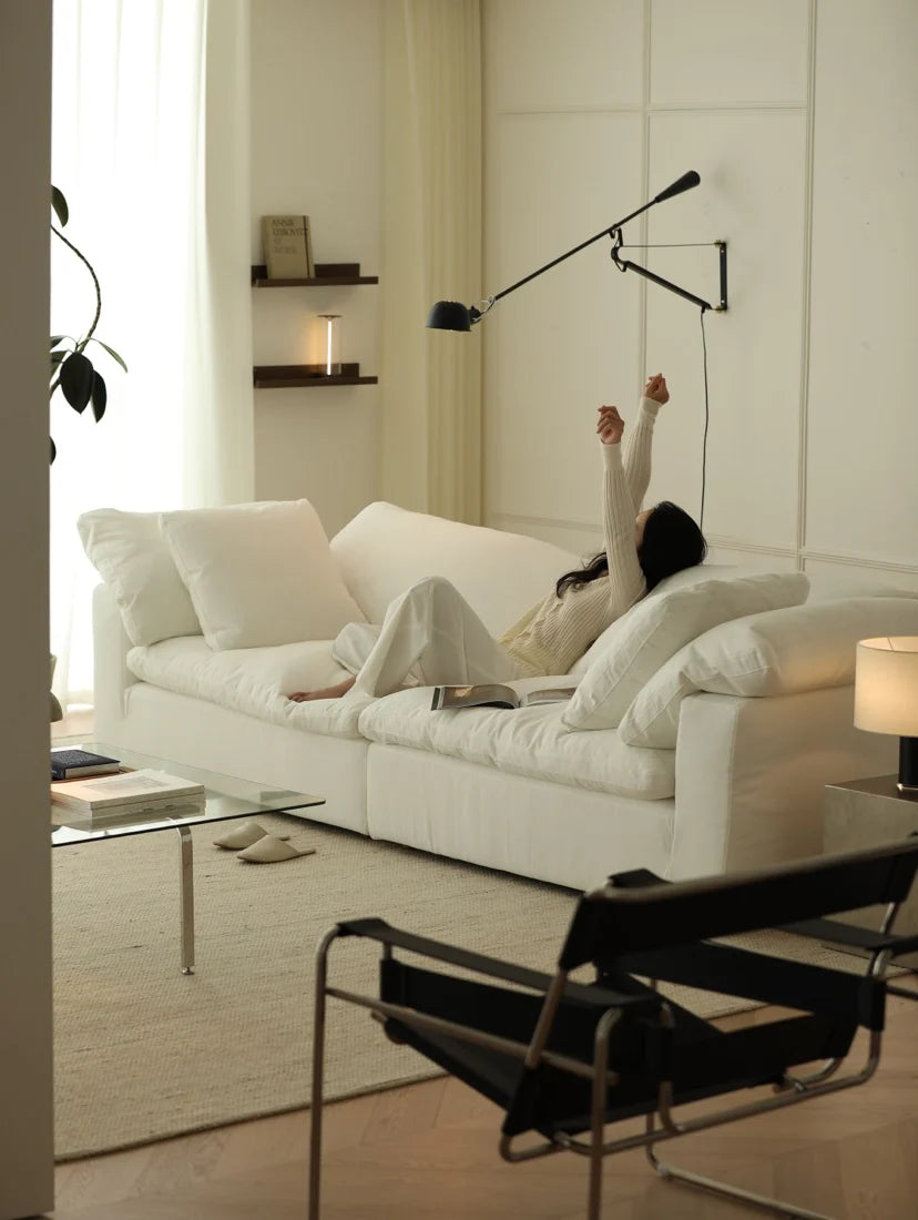 Person stretching in a modern living room with a white sofa and minimal decor.