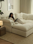 Woman reading a book on a large white sofa in a cozy living room.