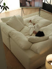 Person lying on a large white sofa watching TV in a cozy living room.