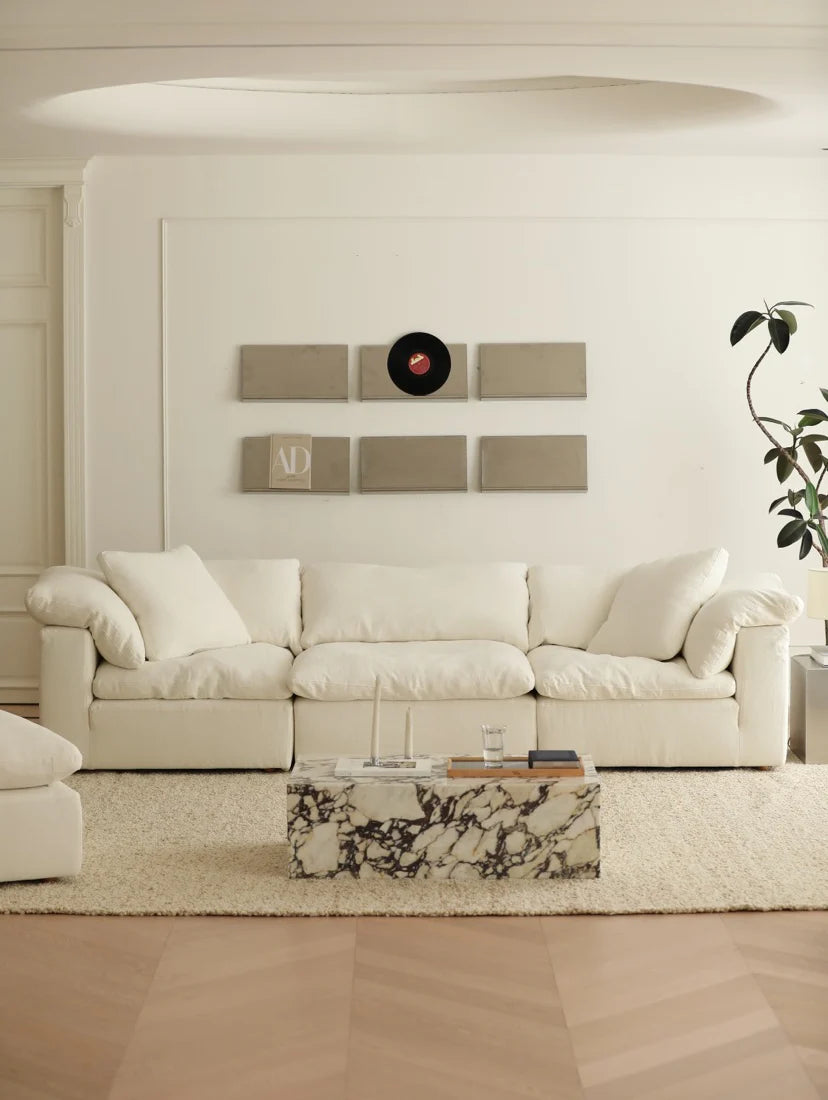 Modern living room with a white sofa, marble coffee table, and decorative wall art.