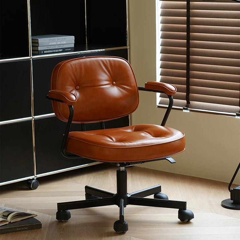 Brown leather office chair in a room with a window and books.