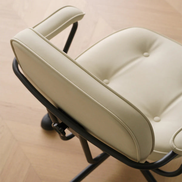 Close-up of a beige cushioned chair with black metal frame on a wooden floor.