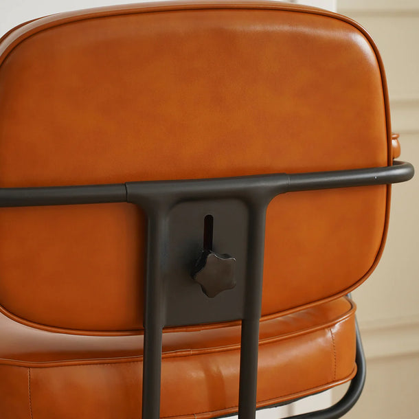 Close-up of a brown leather chair with black metal frame on a beige background