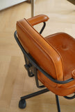 Brown leather office chair with black metal frame on a wooden floor