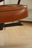 Close-up of a brown leather chair seat with a blurred background