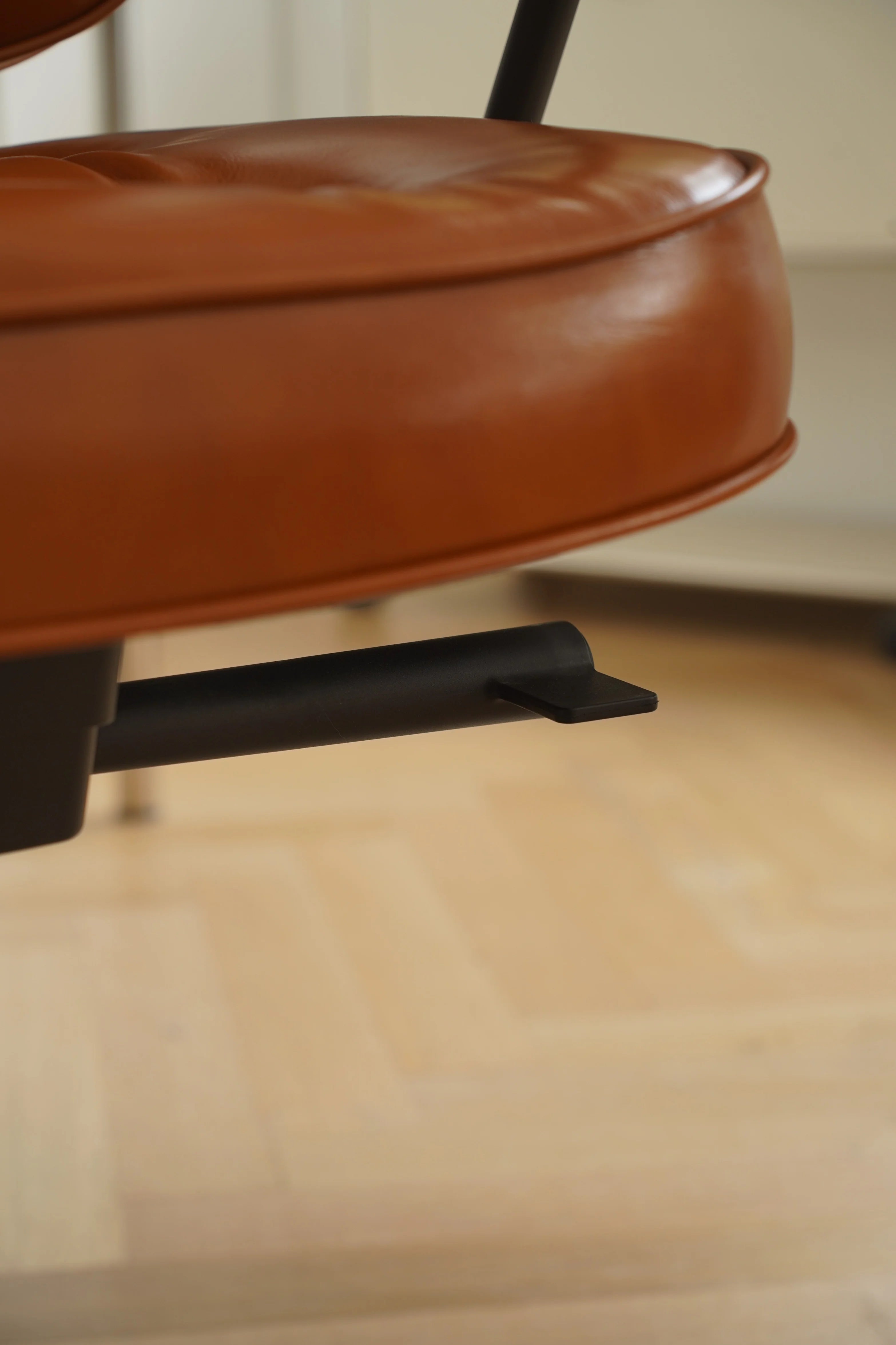 Close-up of a brown leather chair seat with a blurred background