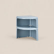 A light blue modular corner stool or side table made of smooth molded plastic, shown stacked in two units against a solid beige background.