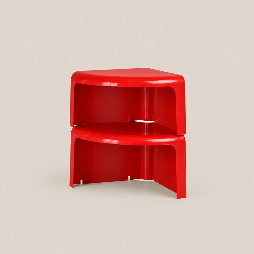 A pair of bright red, modular plastic corner side tables stacked together, set against a solid light beige background.