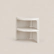 A pair of white plastic corner shelf risers stacked together on a light beige background.