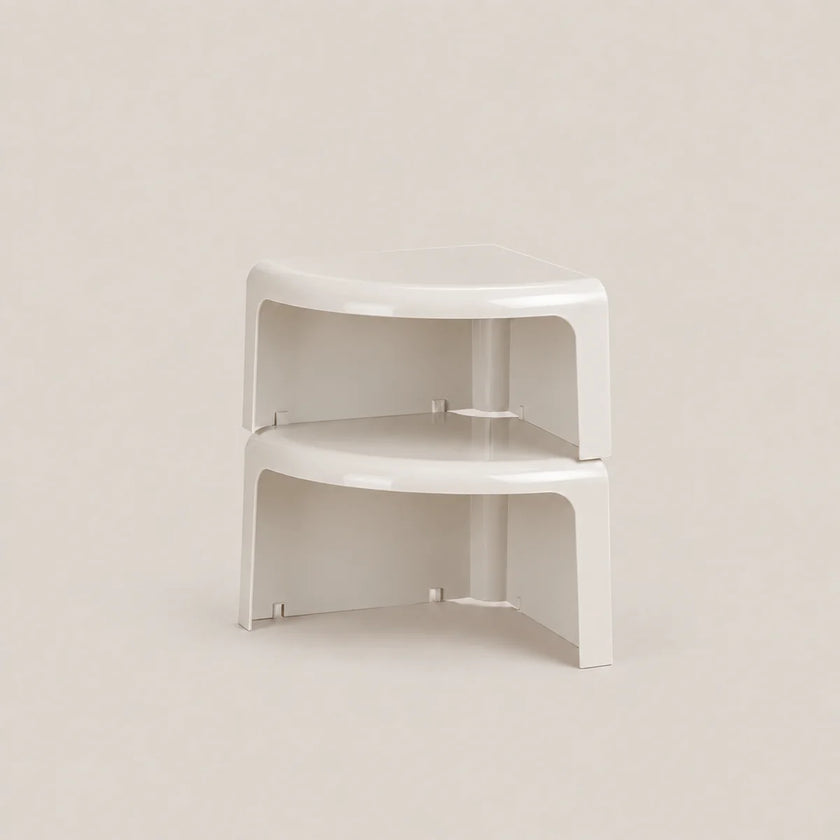A pair of white plastic corner shelf risers stacked together on a light beige background.