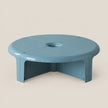 A light blue modular plastic table with a circular top and three intersecting legs, shown on a solid beige background.