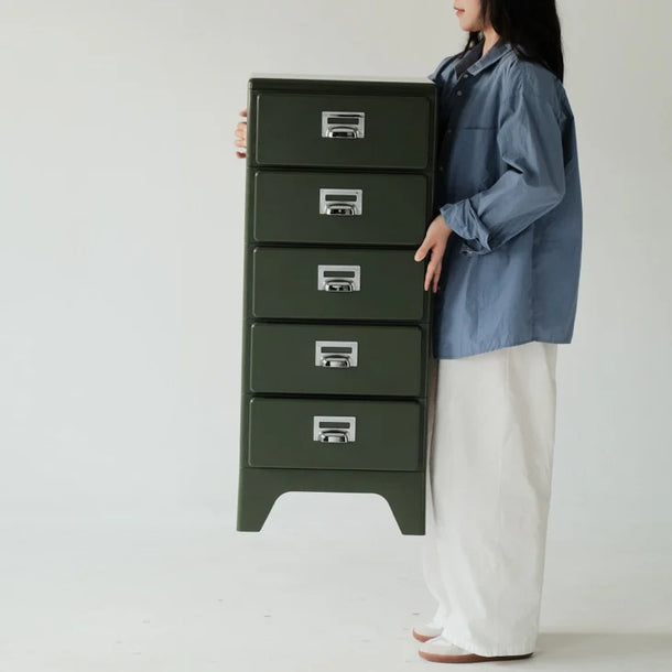 Person holding a green metal chest with multiple drawers on a white background