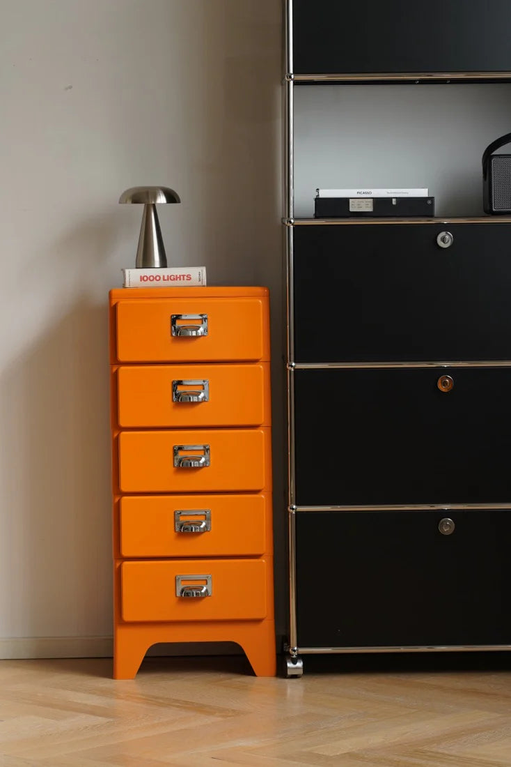 Orange dresser with silver handles next to a black dresser with a TV on top.