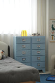 Blue dresser with multiple drawers in a bedroom setting.
