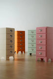 Four colorful filing cabinets of different sizes on a wooden floor.