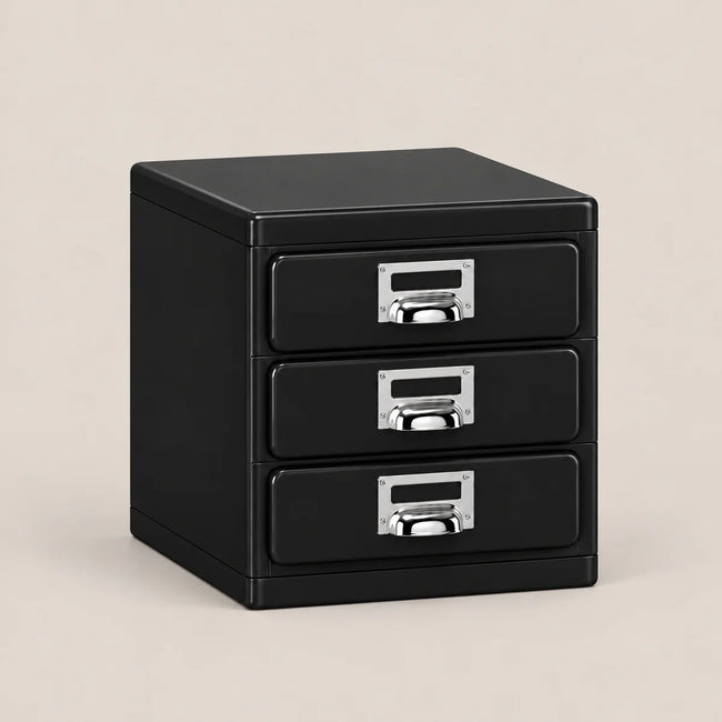 A black three-drawer file cabinet with silver metal pull handles and label slots, shown on a plain beige background.