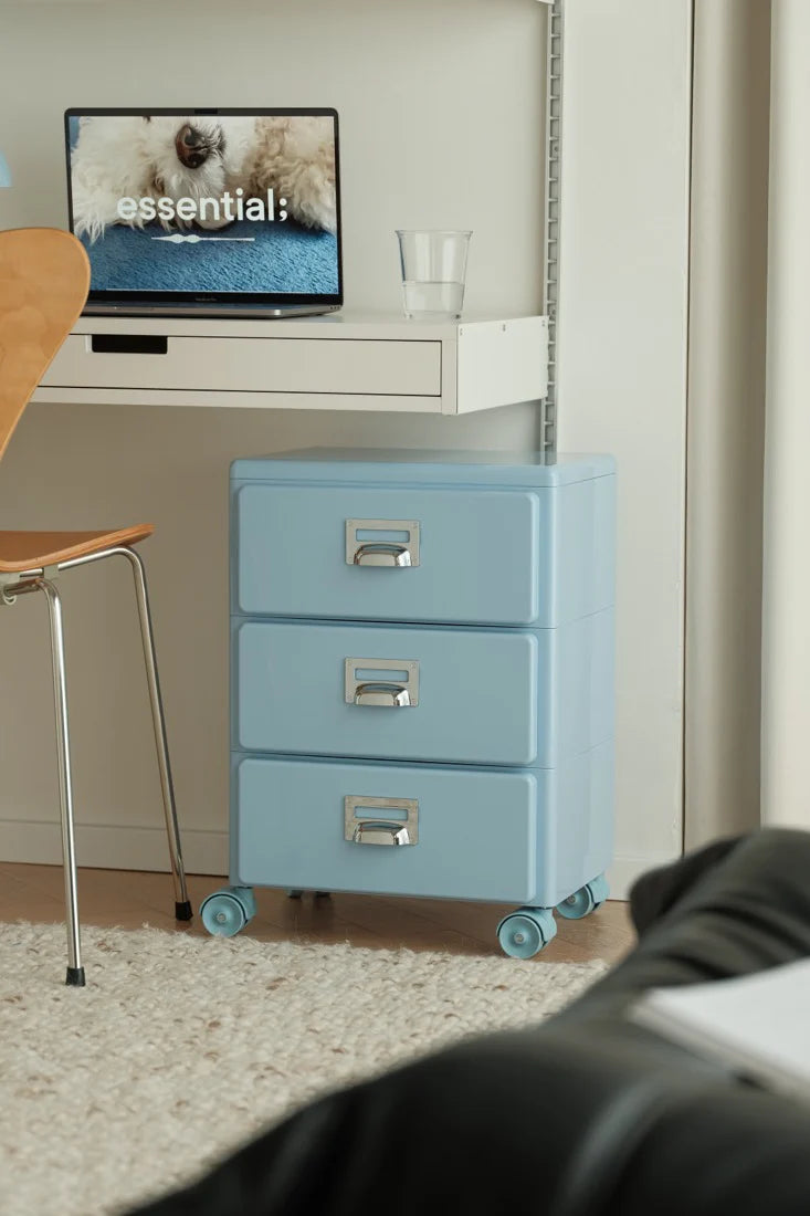 Blue rolling file cabinet in a home office setting with a computer monitor displaying a dog image.