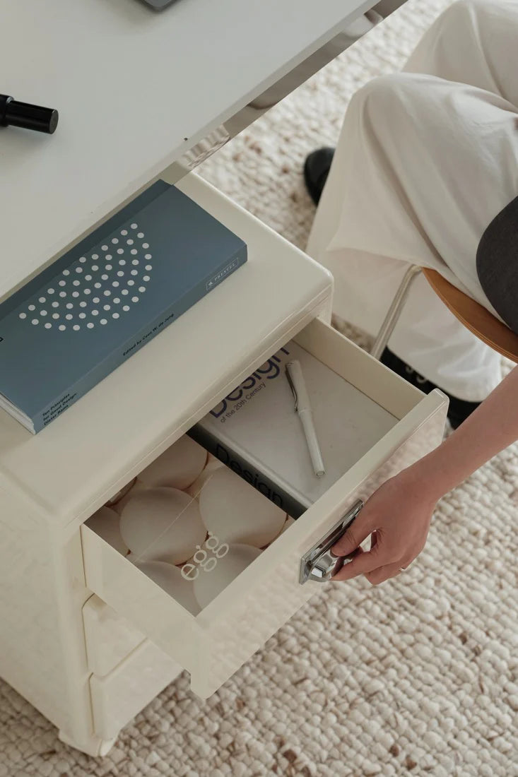 Person opening a drawer in a small table with items inside.