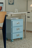 Blue file cabinet with three drawers in a room setting.