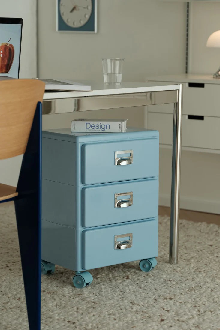 Blue file cabinet with three drawers in a room setting.