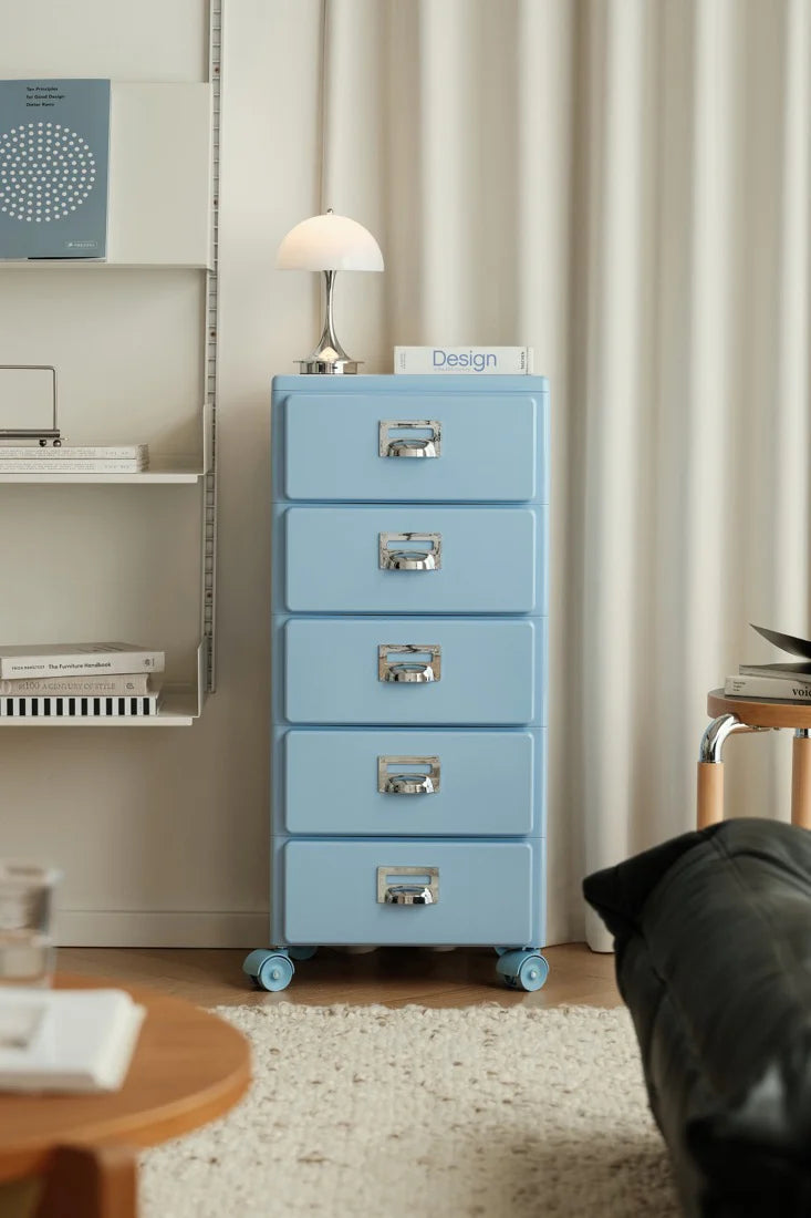 Blue filing cabinet in a room with a lamp and books on a shelf.