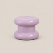A glossy lavender purple mushroom-shaped decorative object, likely a candle holder or small stool, centered on a solid light beige background.