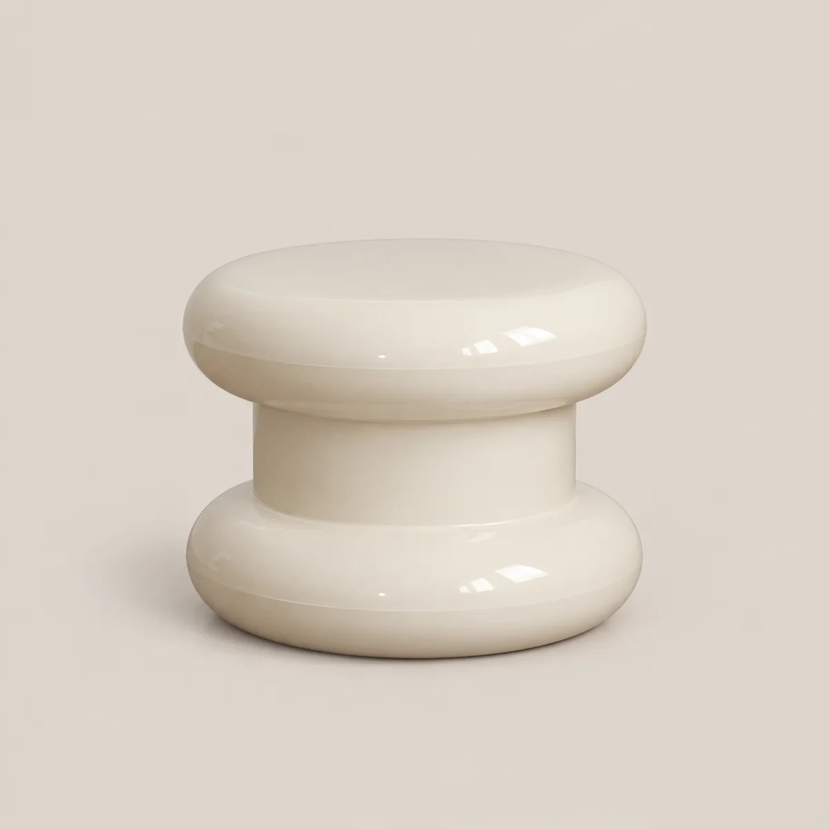 A glossy, two-tiered stool or small table in a warm cream or off-white color, set against a solid, neutral beige background.