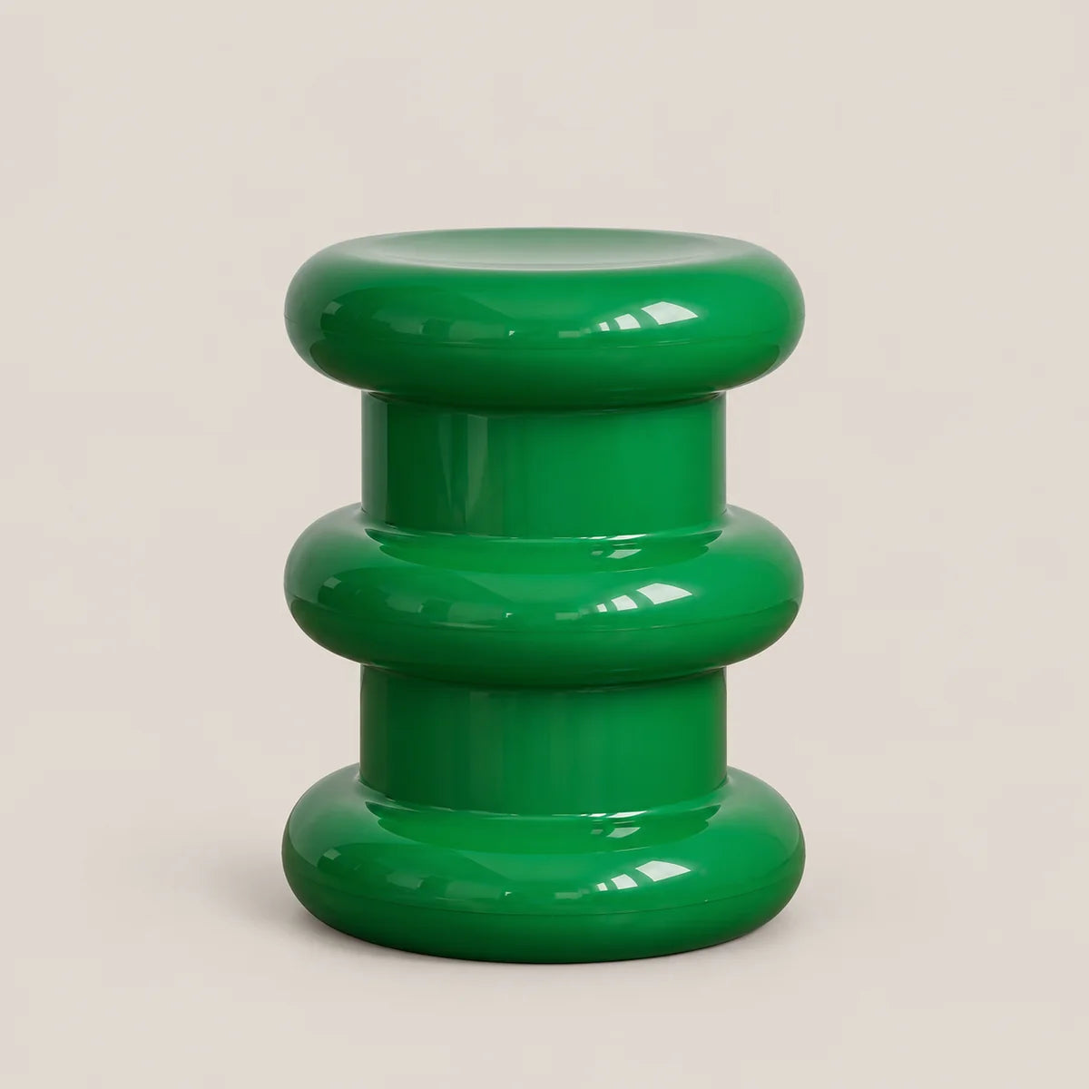 A glossy green modern stool with a stacked, rounded tiered design, photographed against a solid light beige background.