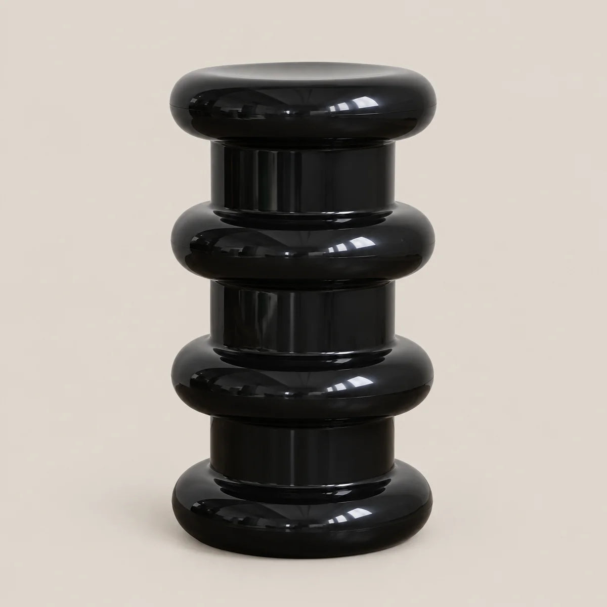 A glossy black modern pedestal stool with stacked, rounded cylindrical tiers on a light beige background.