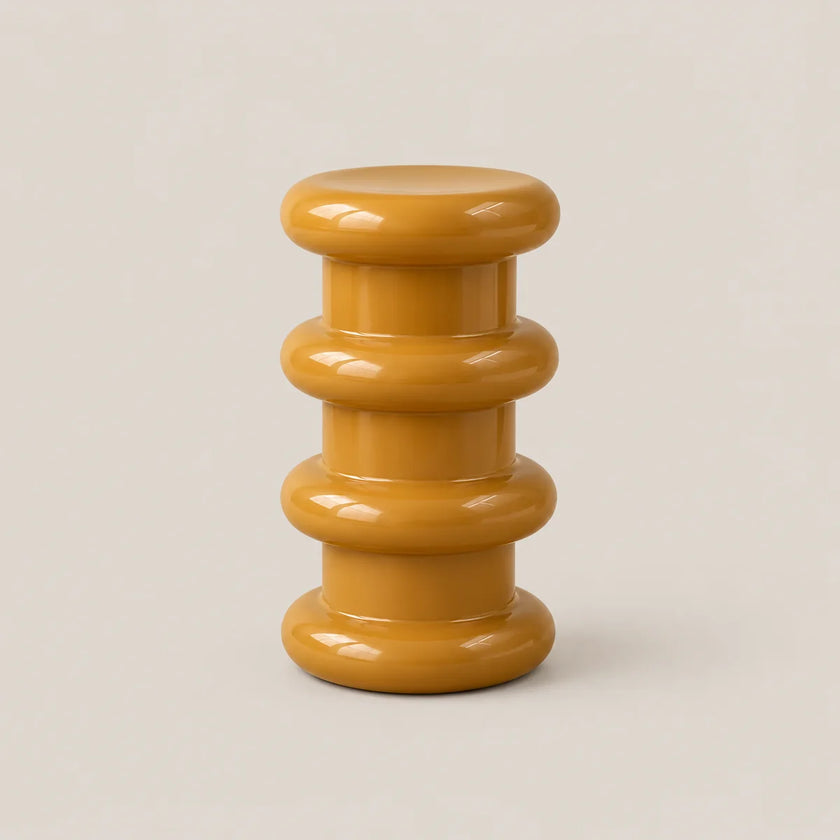 A glossy mustard yellow side stool with a stacked, rounded tiered design on a light beige background.