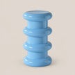A light blue modern pedestal stool with a stacked, ribbed circular design, shown on a solid beige background.