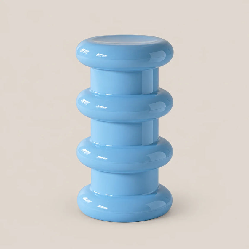 A light blue modern pedestal stool with a stacked, ribbed circular design, shown on a solid beige background.