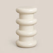 A glossy ceramic side stool with a stacked, ribbed design in a warm cream color, set against a solid light beige background.