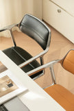 Modern office chair with a metallic frame and black seat in an office setting.