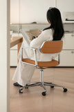 Person sitting at a desk in a modern office setting, using a laptop.