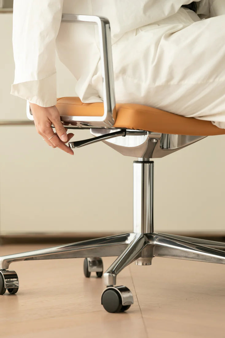Person sitting on a modern office chair with wooden seat and metal frame.