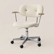 An adjustable office chair with a textured cream bouclé upholstered seat and backrest, chrome metal frame and base, and light wood armrest caps, shown on a plain beige background.