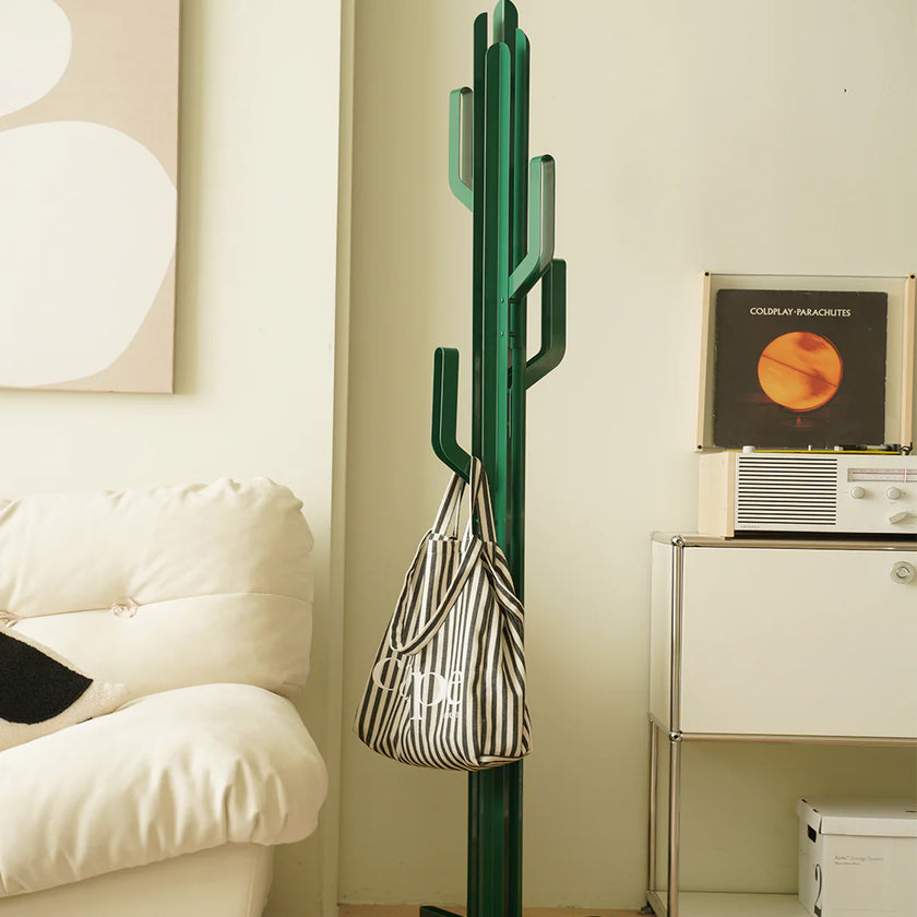 Green cactus-shaped coat rack with a striped bag against a light-colored wall.