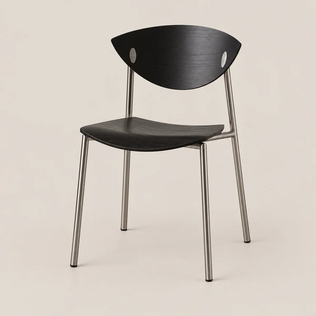 A modern black chair with a curved wooden seat and backrest, featuring two circular cutouts in the backrest and a slim silver metal frame, set against a solid light beige background.