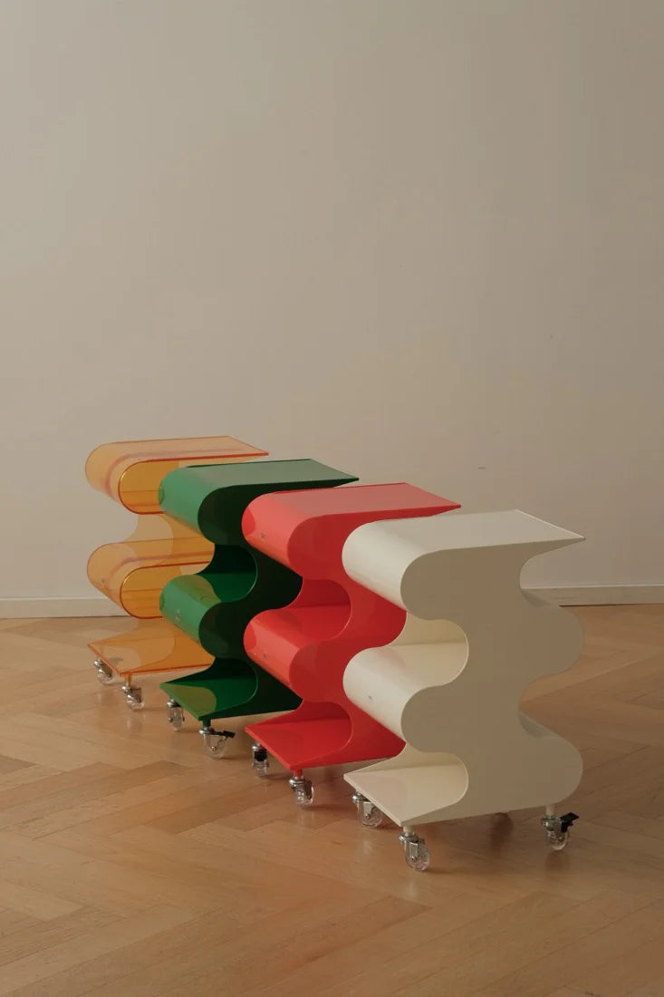 Colorful wavy table on wheels against a plain wall