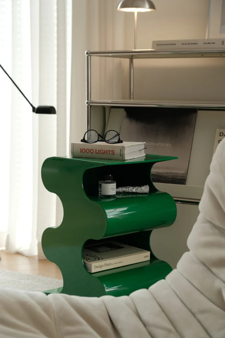 Green side table with books and glasses in a room setting