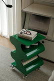 Green rolling cart with books and glasses on a carpeted floor.