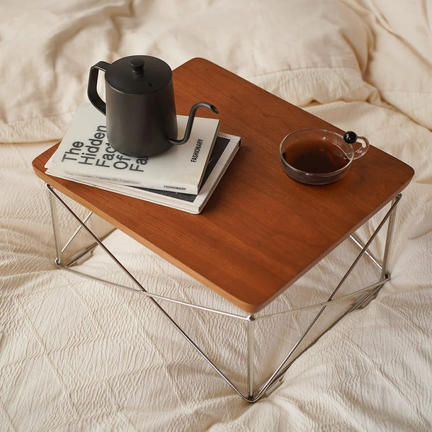 Wooden tray with a teapot, glass of tea, and book on a bed